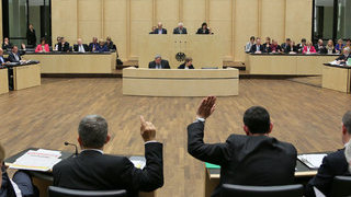 Foto: im Vordergrund heben zwei Mitglieder des Bundesrates die Hand zur Abstimmung
