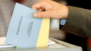 Foto: Hand mit Wahlzetteln