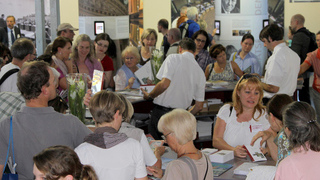 Foto: Besucher vor einem Stand mit Informationsmaterial