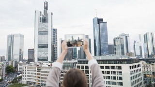 Frau macht mit einem Tablet ein Foto einer Skyline