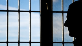 Foto: Mann vor einem vergitterten Fenster