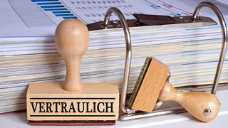 Foto: Aktenordner und ein Stempel mit Aufschrift vertraulich