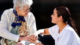 Foto: Pflegerin und eine ältere Dame im Rollstuhl