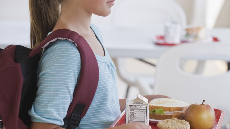 Foto: Kind mit Schulranzen und Tablett mit Essen