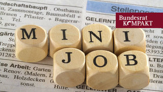 Foto: Mehrere Buchstabenwürfel zum Wort Minijob auf Zeitungsauschnitt Stellenangebote liegend